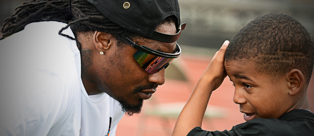 Marshawn Lynch with a boy at a Fam 1st football camp
